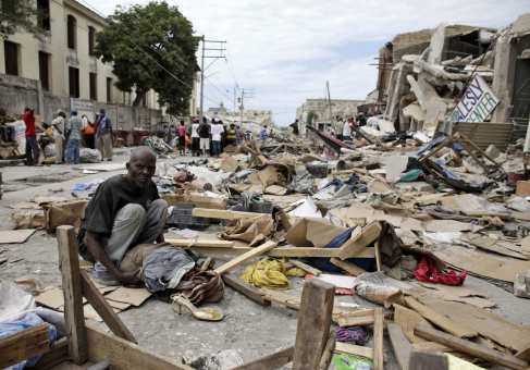A resident sits at a destroyed area after a major earthquake hit the capital Port-au-Prince